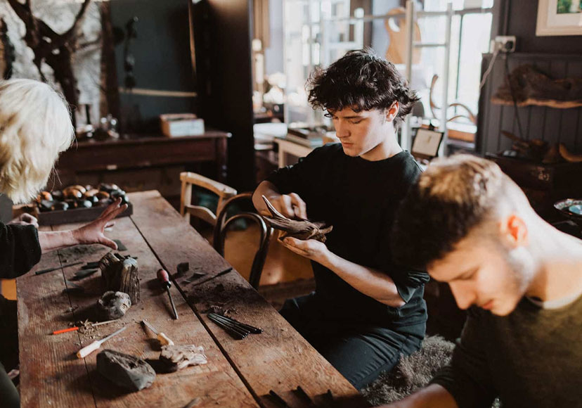 Artists hand carving various pieces at the Celtic Roots Studio workshop.