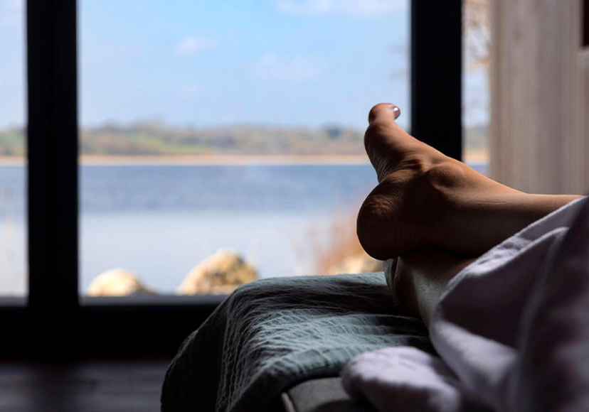 Person relaxing in lakeside room at Cedarwood Spa.